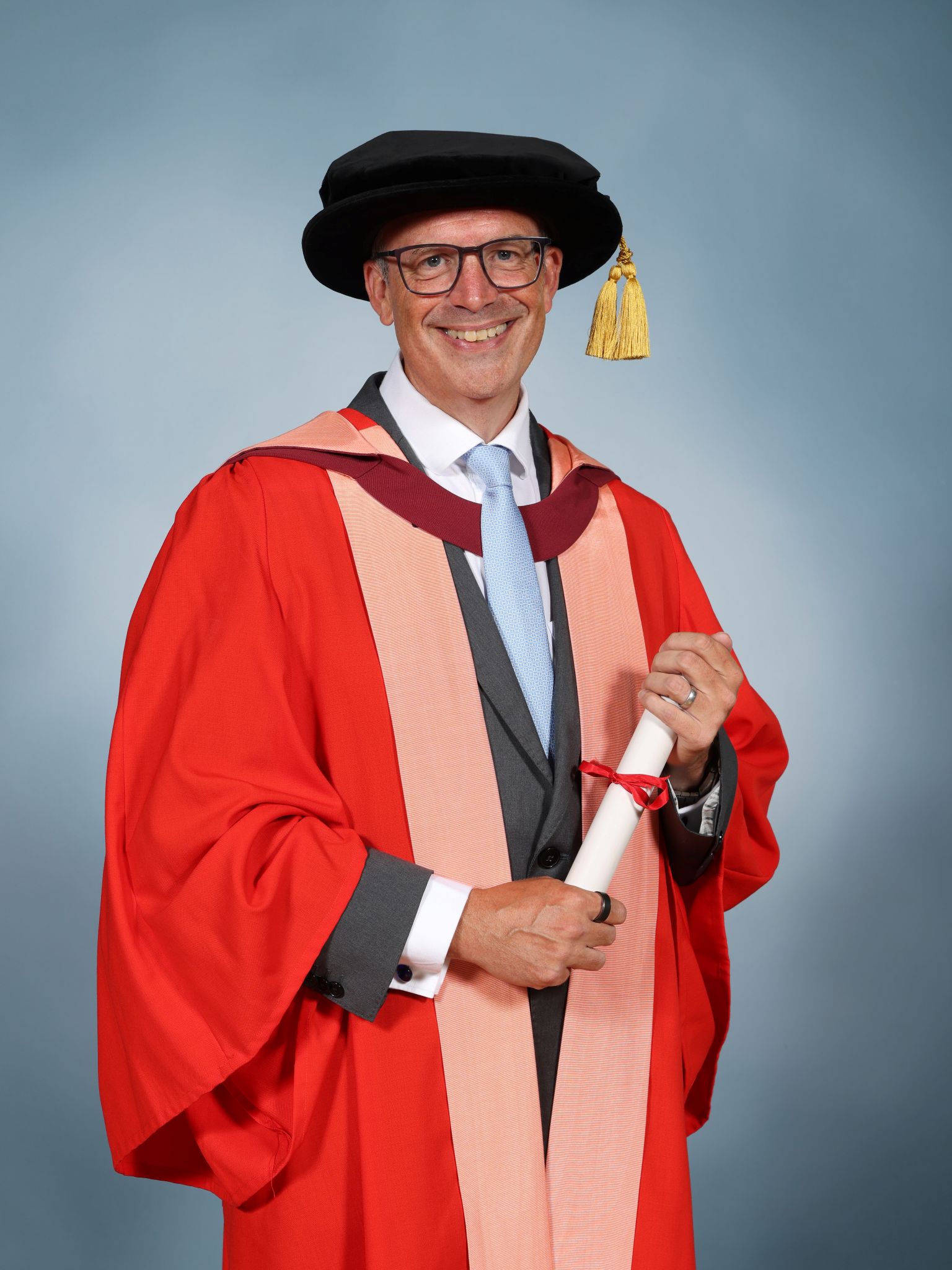 Jonathan Phillips wearing a mortar board and holding a parchment